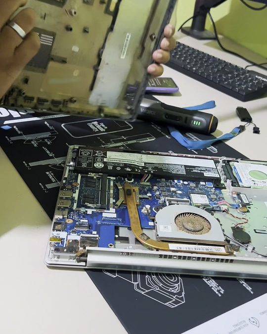 Notebook aberto na bancada da Joadetech durante o conserto