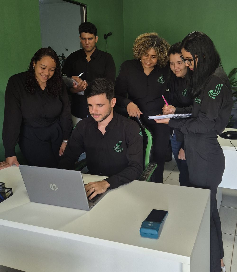 Joade no notebook com a equipe em volta